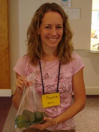 A co-op member holds up a bag of avocados she has just weighed for another member's order.